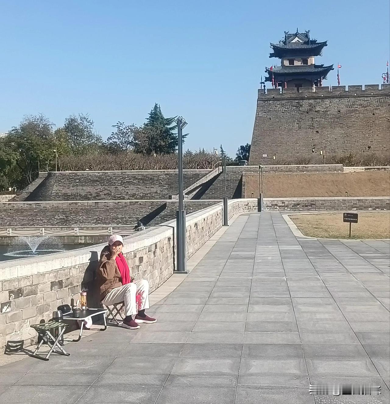 在古老城墙下，享受宁静的午后时光。品茶悟道，研究股票，一位老大叔看书雷达著作～～