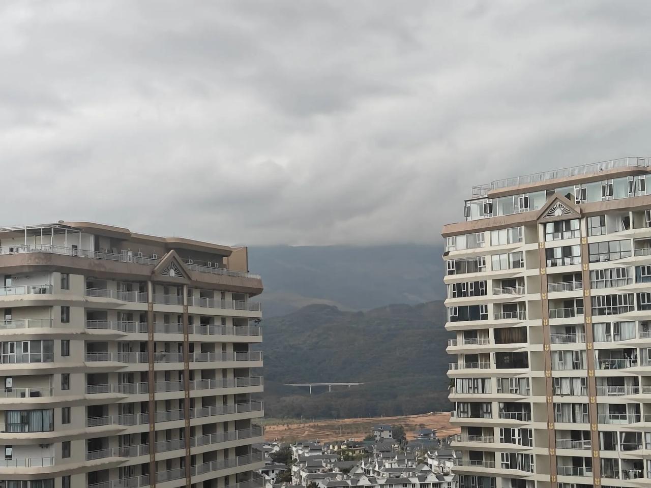 黑褐色云彩，依依不舍地压在南路山弯曲的山峦上。视觉效果，由远及近，南路山由青到淡