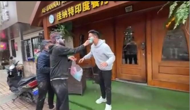 一群印度人在南京印度餐厅门口旁若无人地过洒红节，互相涂抹着彩色颜料，挥撒不知名的