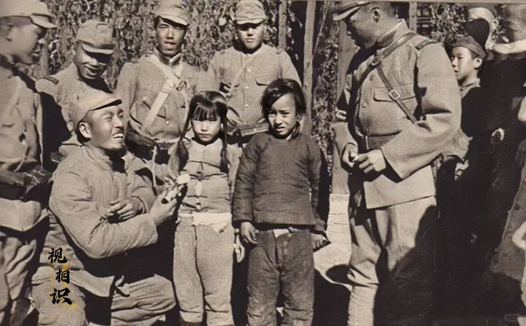 抗战时期，日军“伪亲善”的宣传照，画面中一群日军围着两个小女孩，其中一名日军蹲了...