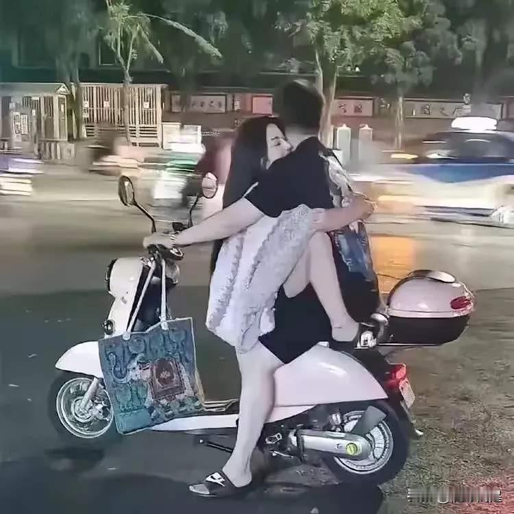 一对情侣在雨中拥抱，甜蜜又浪漫。电动车这样坐人也可以，真是大开眼界。