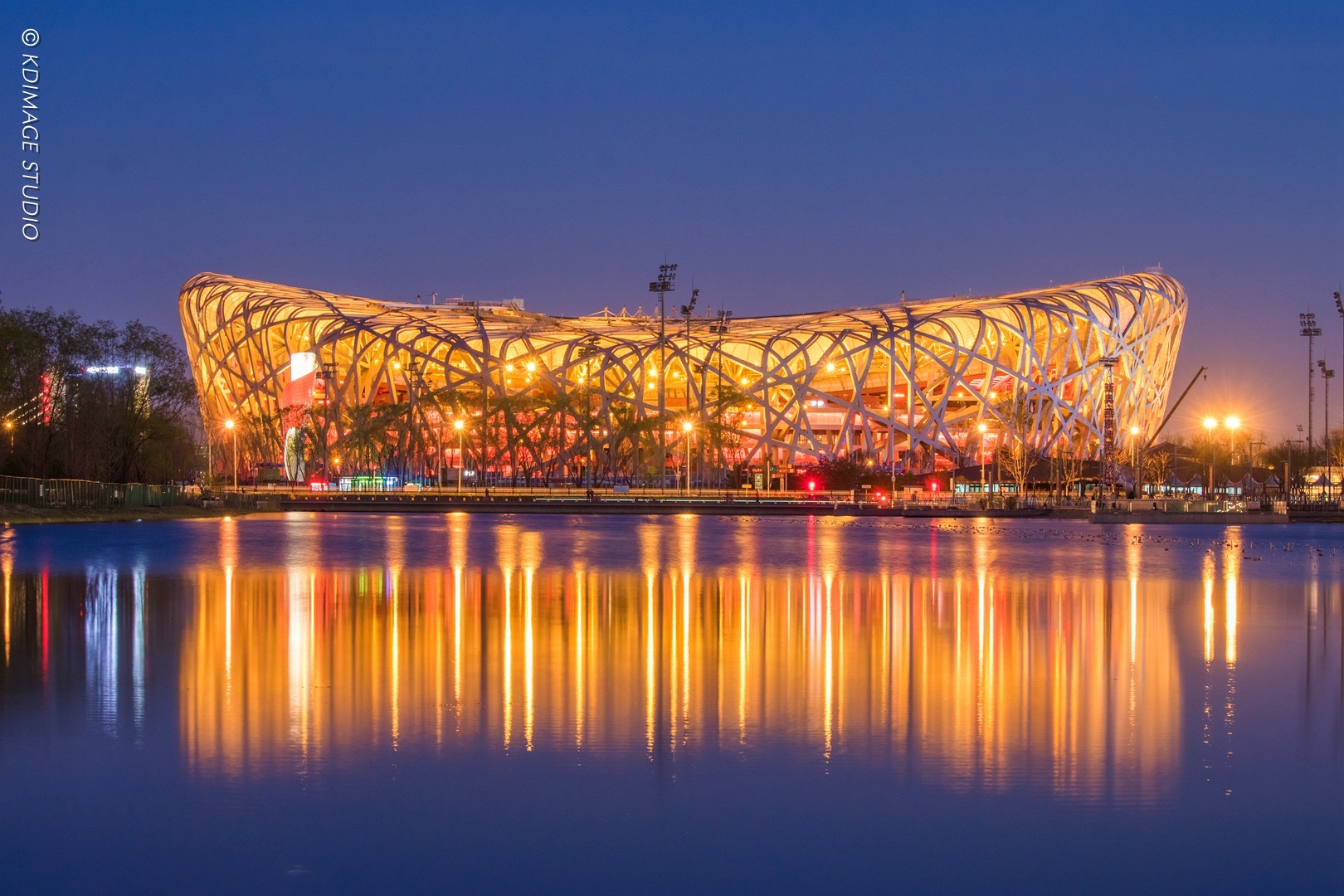 新年第一帧镜头夜色如墨，北京鸟巢的钢铁筋骨在璀璨灯火中化作刚毅的图腾，伫立于天地