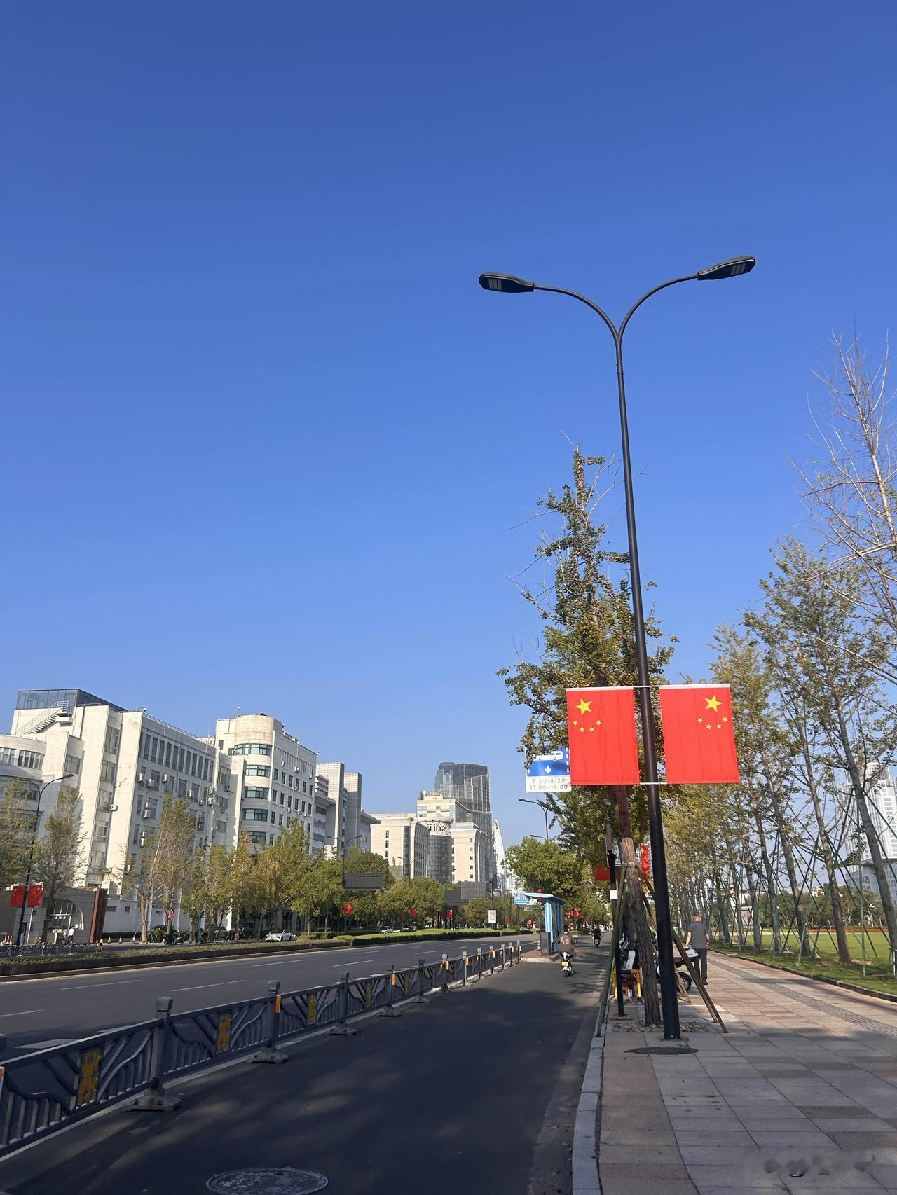 行走在市府大道，道路两侧灯杆上整齐悬挂起鲜艳的五星红旗，一面面红旗在阳光的照射下