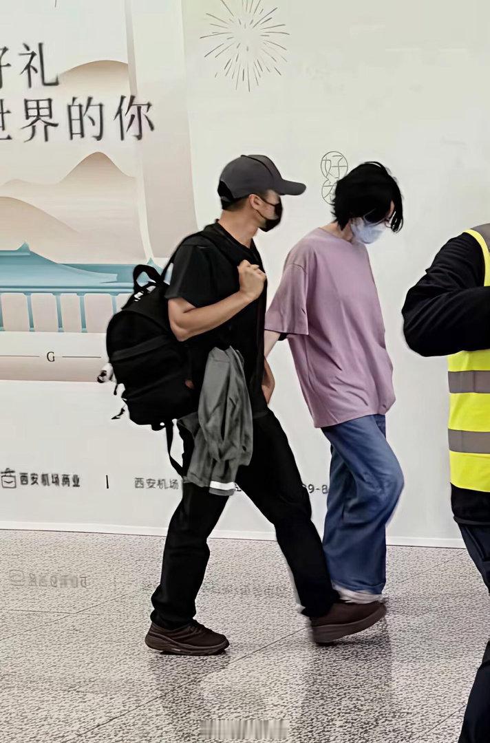 王菲离开西安，她与谢霆锋十指紧扣走机场的画面。 