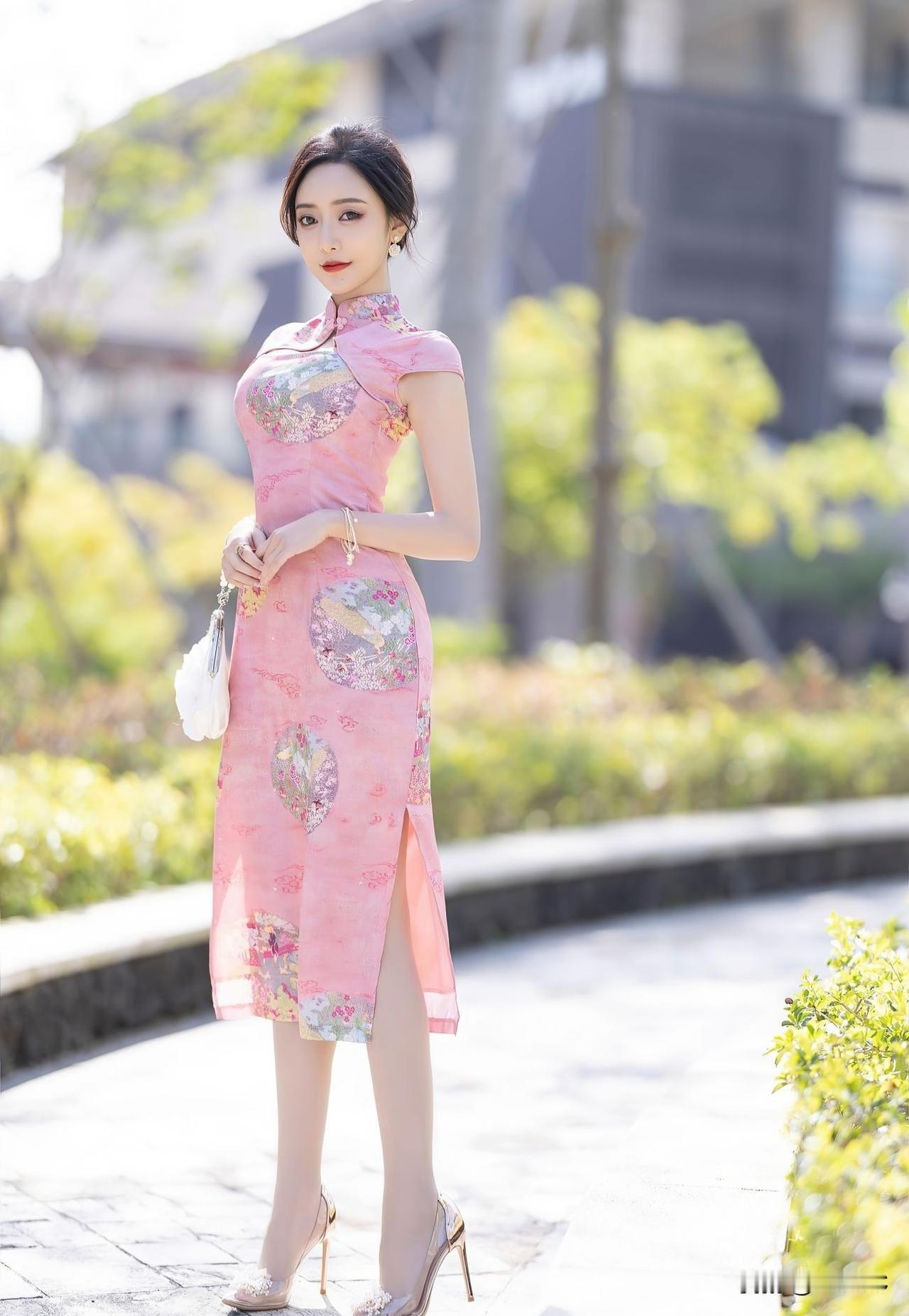 这位女士穿着粉色旗袍，好漂亮！旗袍的剪裁完美贴合她的身材曲线，将女性的柔美展现得