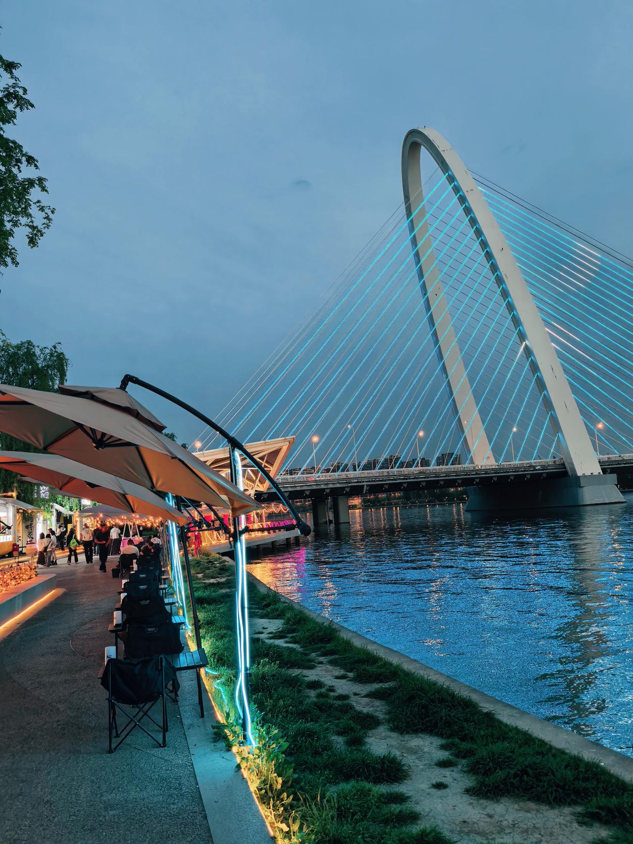 当暮色把天空调成莫兰迪蓝，西安这座城市的温柔便有了形状，桥是弯月坠入人间的骨架，