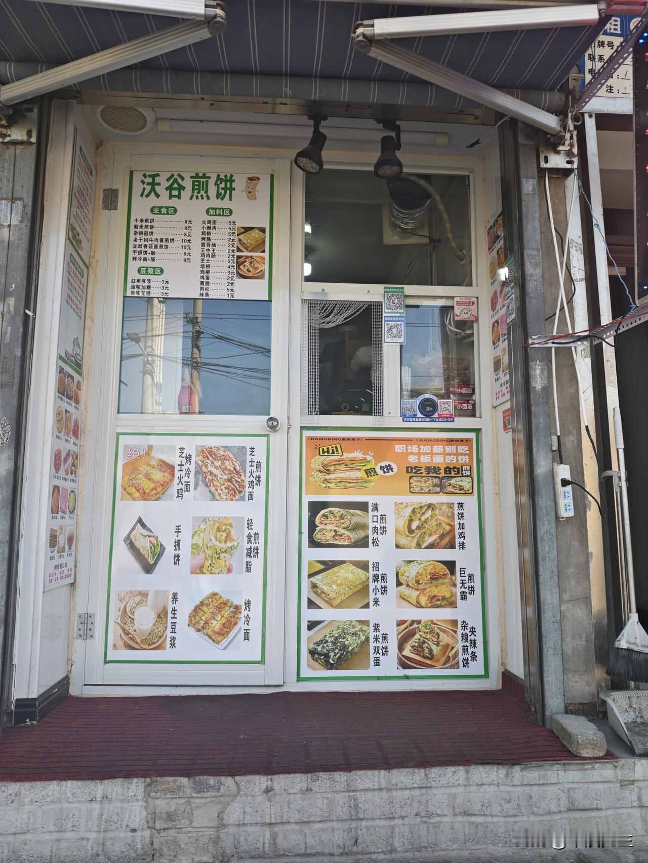 一家煎饼店，门窗上贴满了各类煎饼的图片和价格。小米煎饼：8元；紫米煎饼：8元；杂