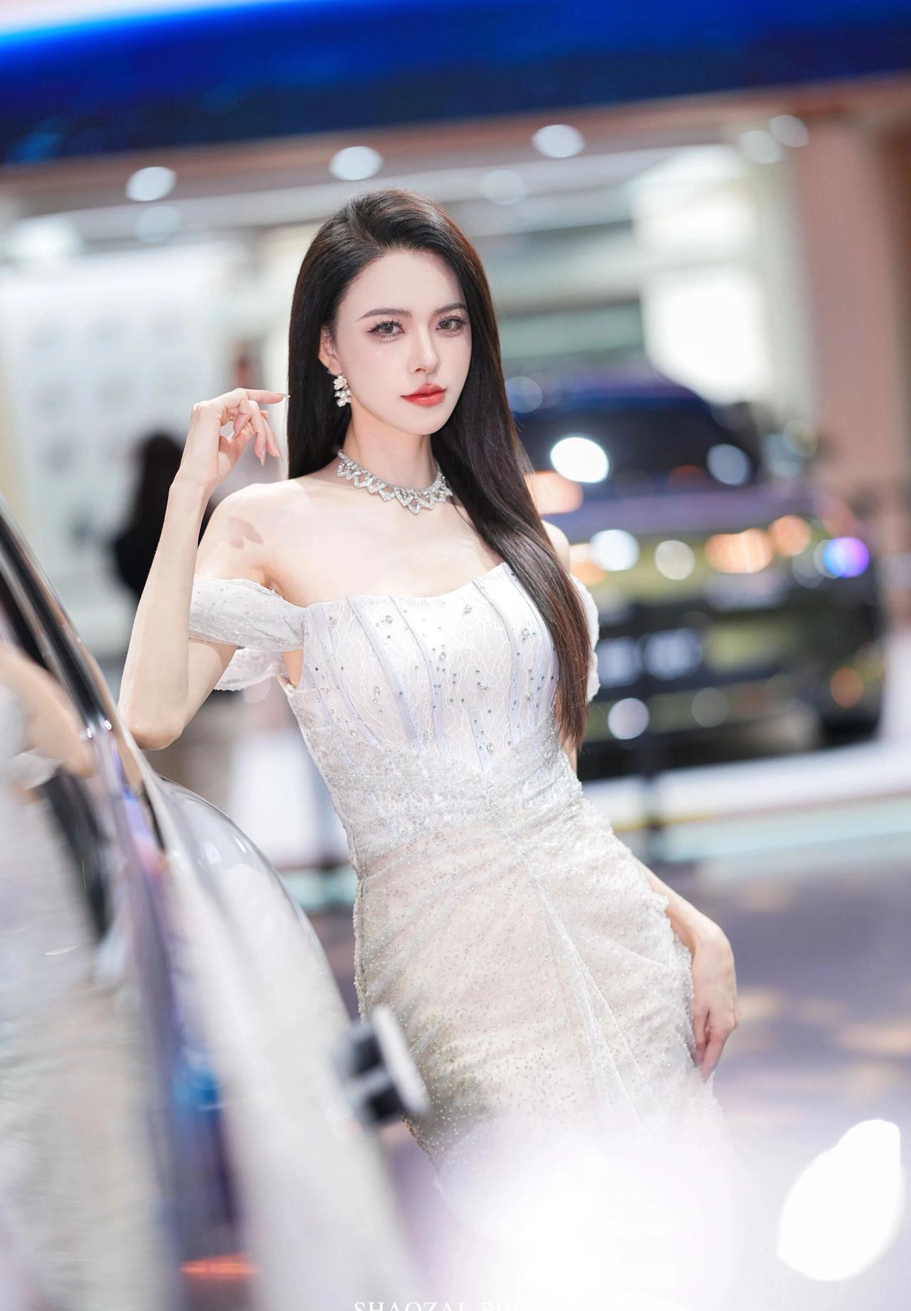 她留着一头乌黑柔顺的长直发，妆容精致，红唇点缀，眼神清澈又带着一丝冷艳。颈间与耳