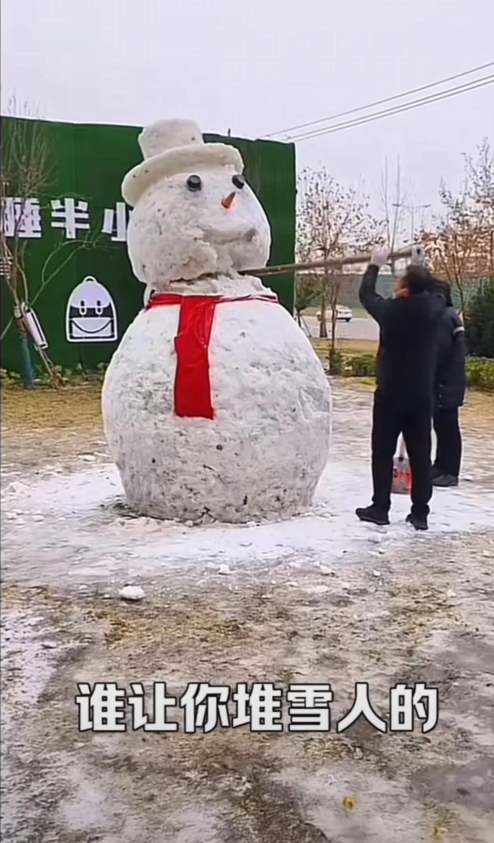 寒冬腊月，有人在路边做了一个漂亮的雪人，还给雪人戴上了一个红色的围脖，吸引着路人