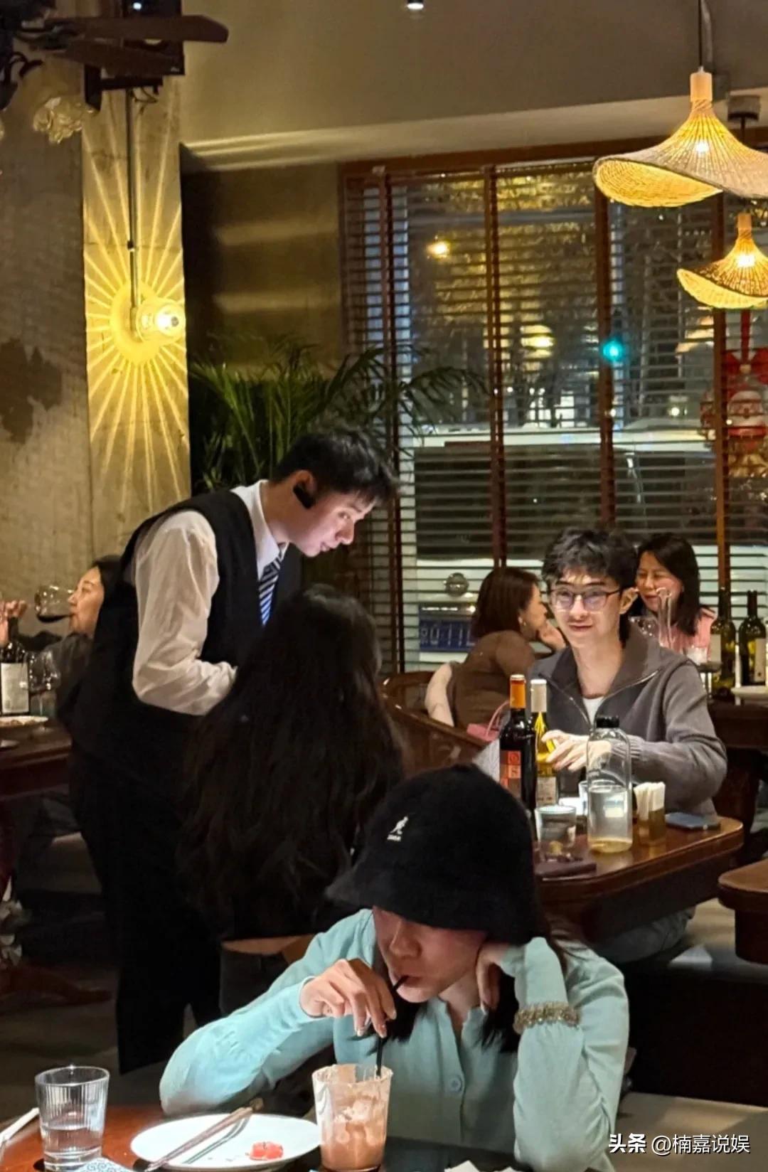 伊能静儿子恩利，在北京一酒吧和女伴聚会。
他戴着眼镜，穿着一件灰色外套，脸看着好