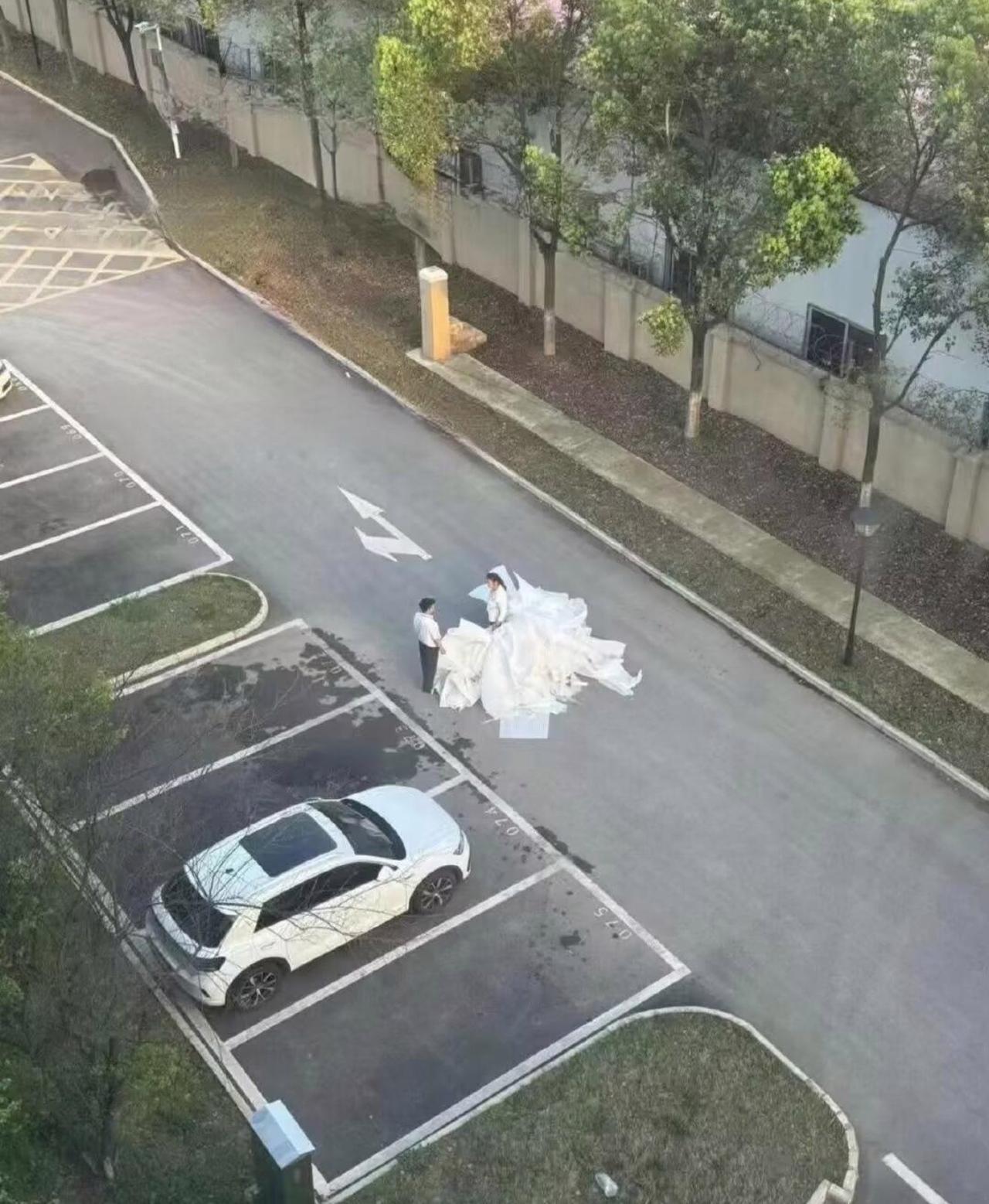 远远从楼上往下瞅，白纱铺了满满一地，一男一女站在路中间，氛围感直接拉满，我还以为
