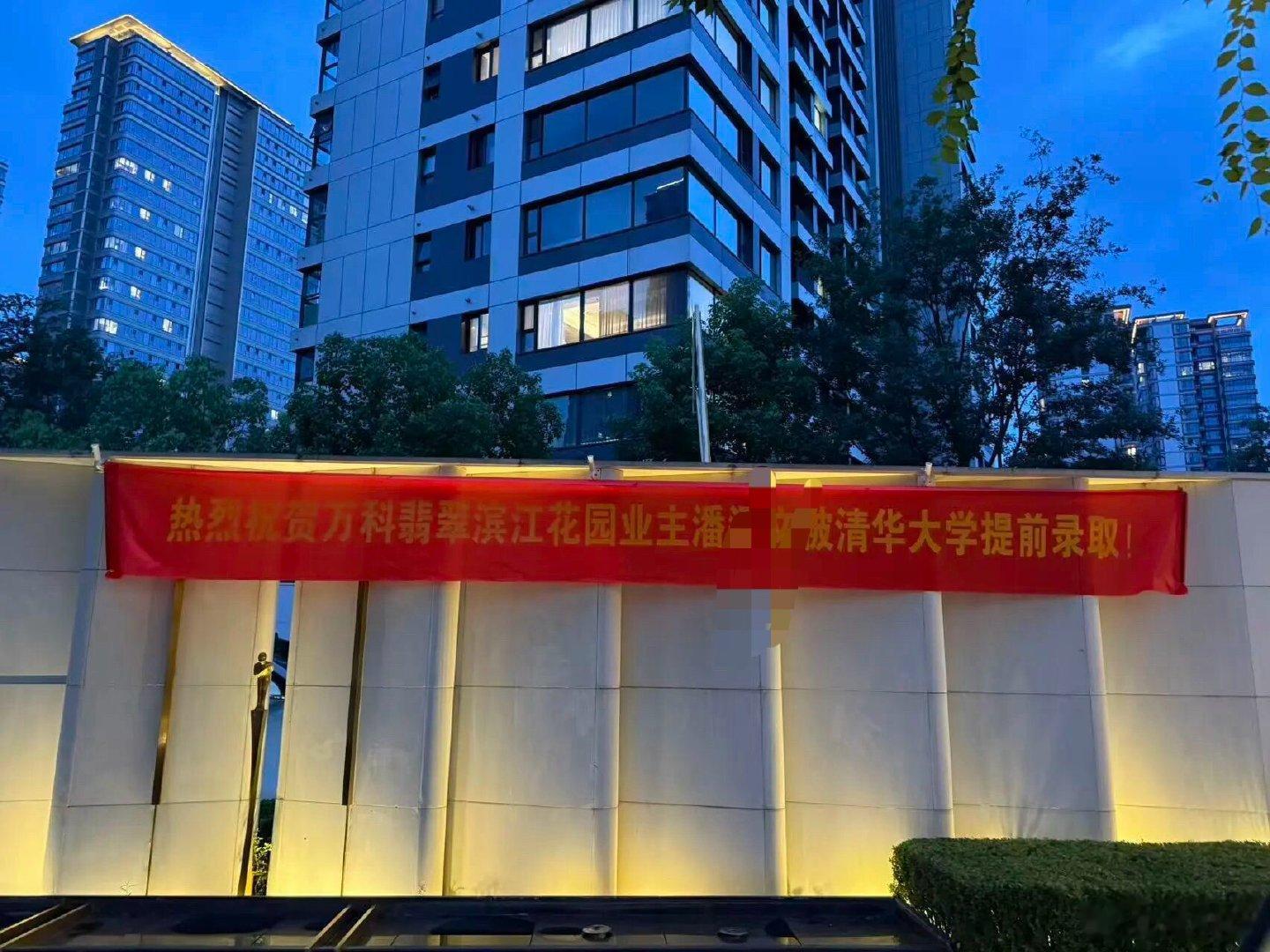 虽然小区房价降了，但学子考上了清华，值得庆贺，横幅拉了起来！多一些优秀学子，确实