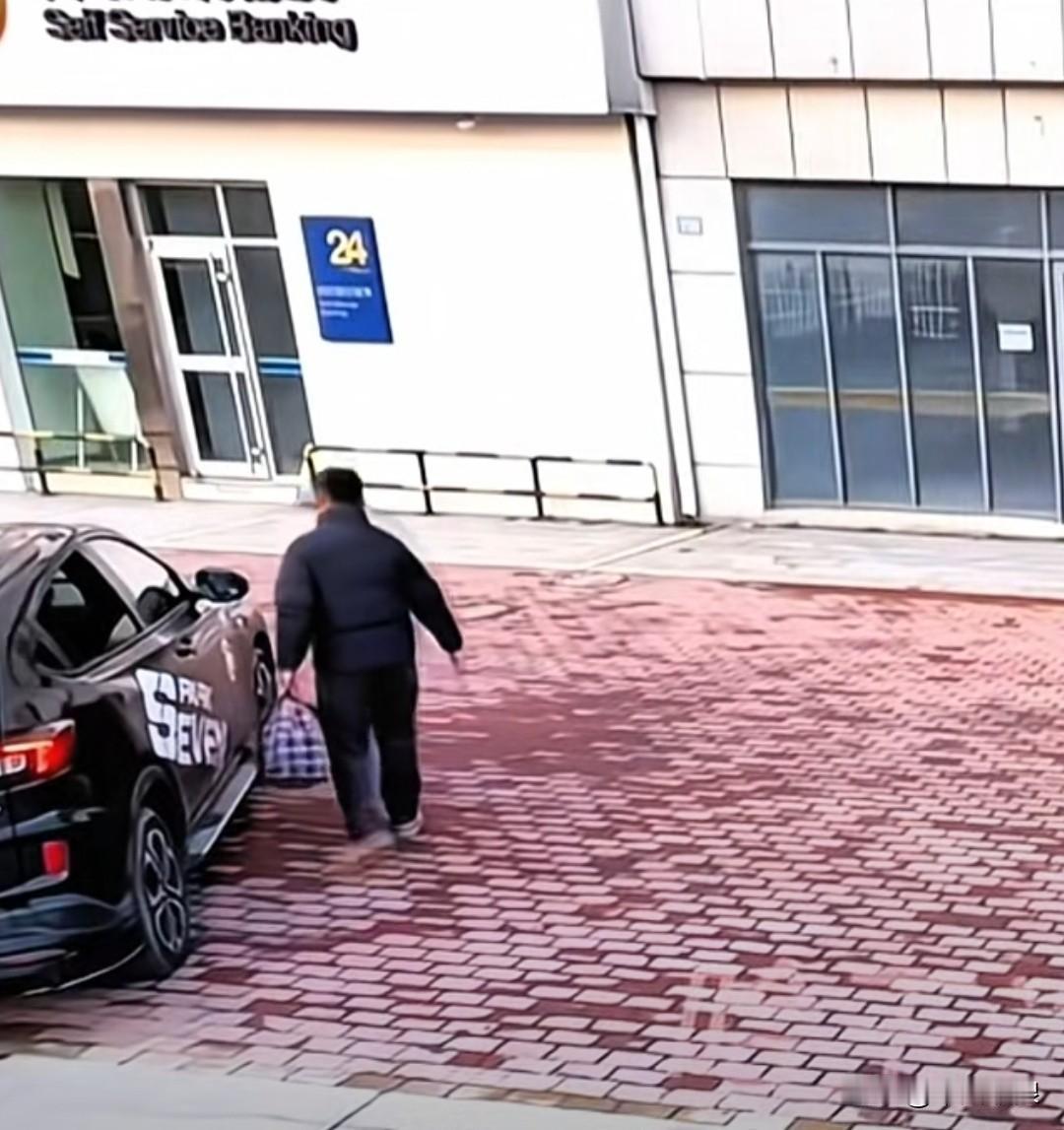 一男子下车后，让狗狗在车内等着，自己拿着一个包去取款机取钱。他被一位蒙着脸的男子