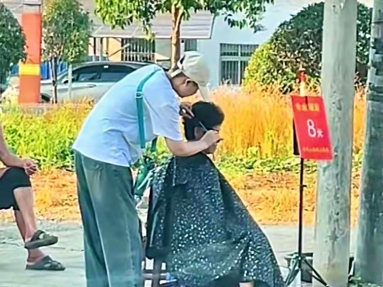 湖北仙桃，街头一个简陋的理发摊，只有一块价格板，两张椅子，老板叫小郑，一个常年戴