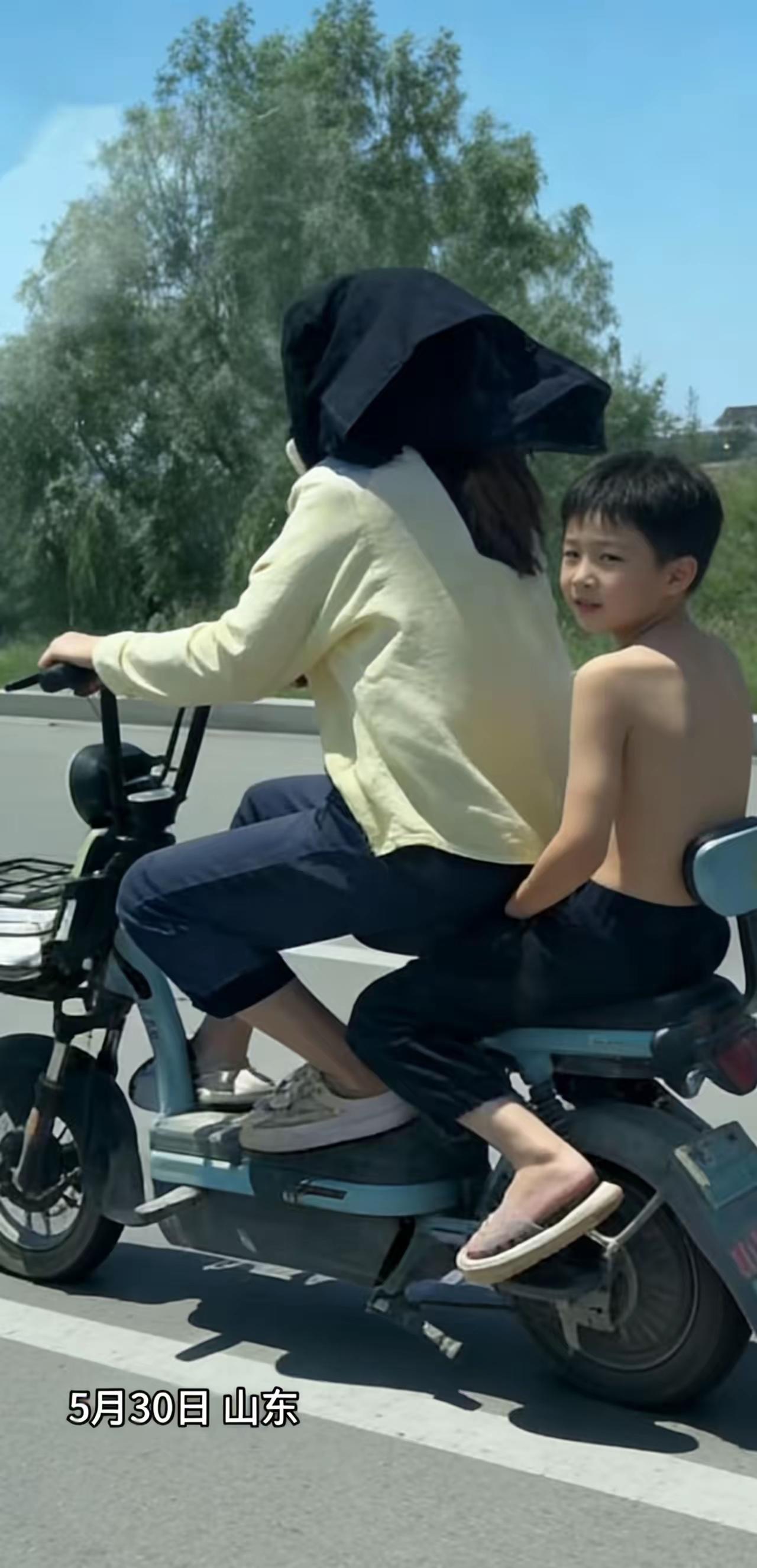 绝对亲生的！
5月30日，山东，妈妈骑着电动车带着儿子，因为太阳大，妈妈怕晒，要