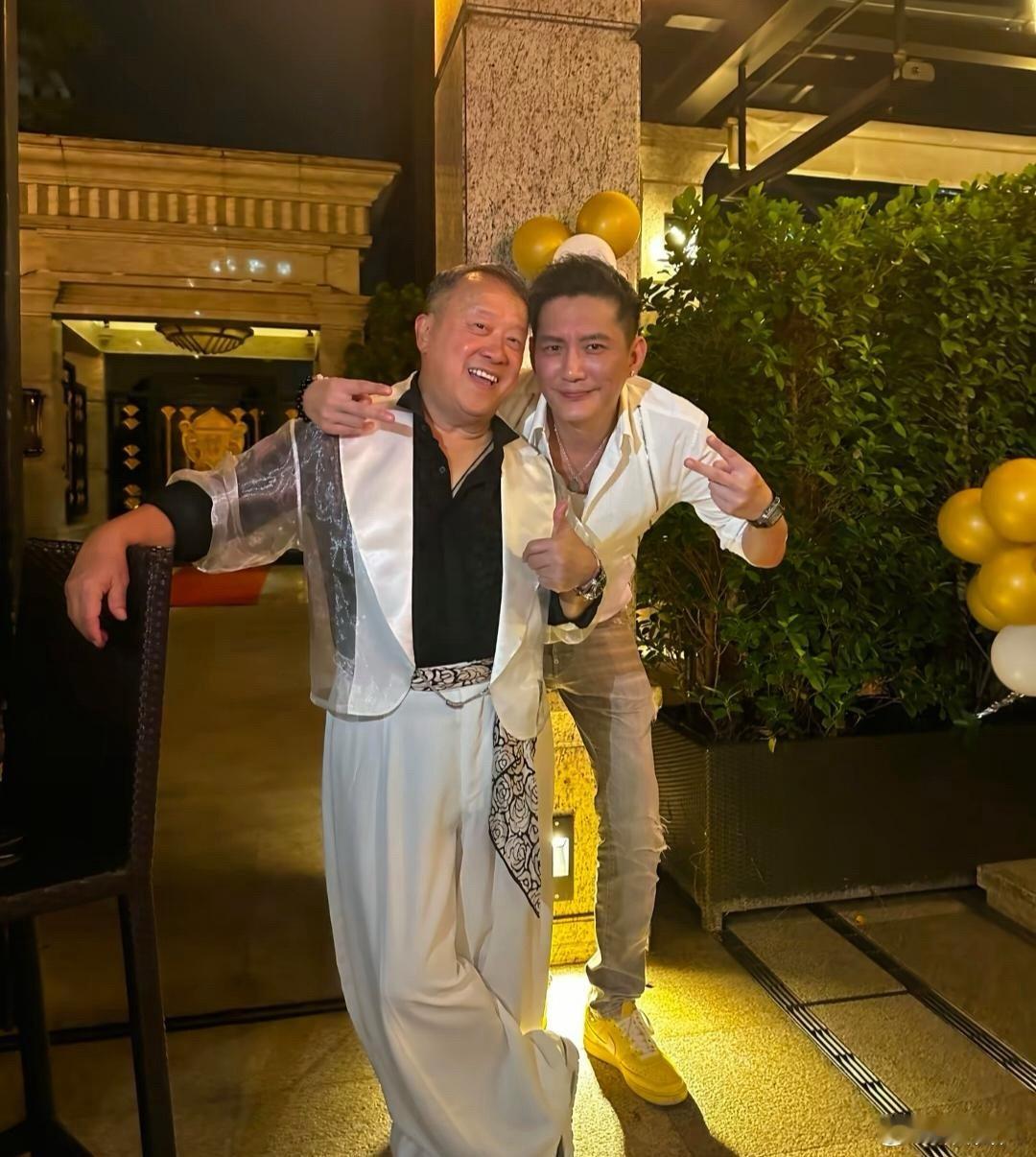 曾志伟在深圳一家五星级酒店庆祝73岁生日，他穿着一身名牌衣服，笑容满面，和一位男