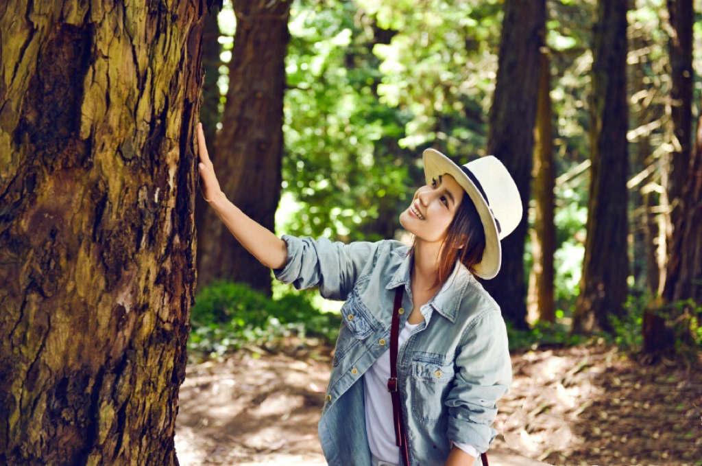 以牛仔衬衫与牛仔裤的休闲穿搭，在林间与街头展现出松弛又治愈的氛围。她轻抚树干，抬