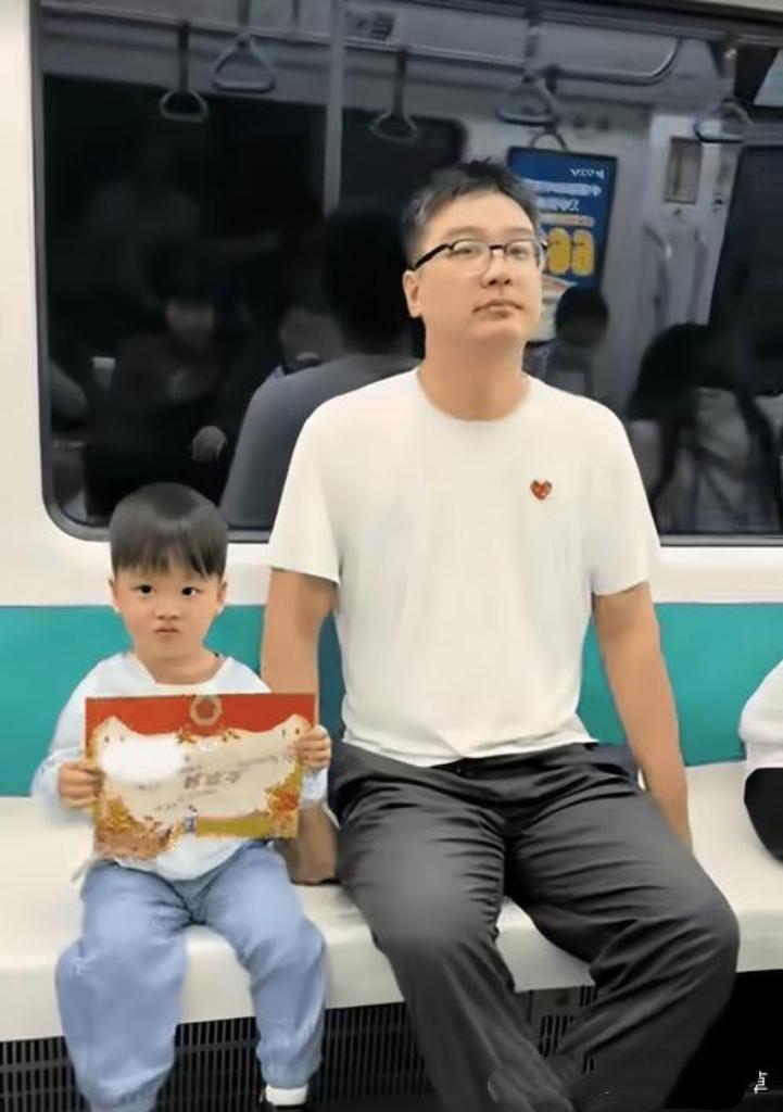 萌娃坐地铁，手举“好孩子奖状”一路不撒手，那骄傲的小模样超可爱！小家伙沉浸在得奖