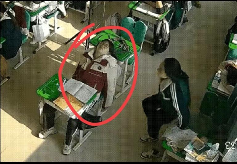 学校午间休息时，一名同学写完作业后靠在椅背上睡着了。旁边的同学见此情景，悄悄把脚