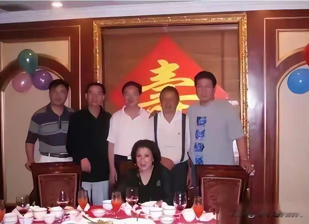 2008年寿宴现场暖意融融，背景大红寿字格外醒目，彩气球点缀两侧，餐桌摆满杯盏佳