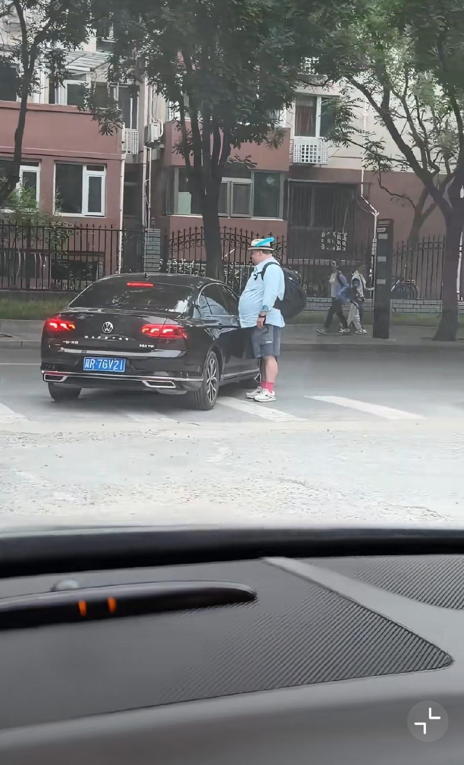 大肚子歪果仁走在斑马线上，一辆车要右转，大肚子停下来，并没有要让黑车走的意思！