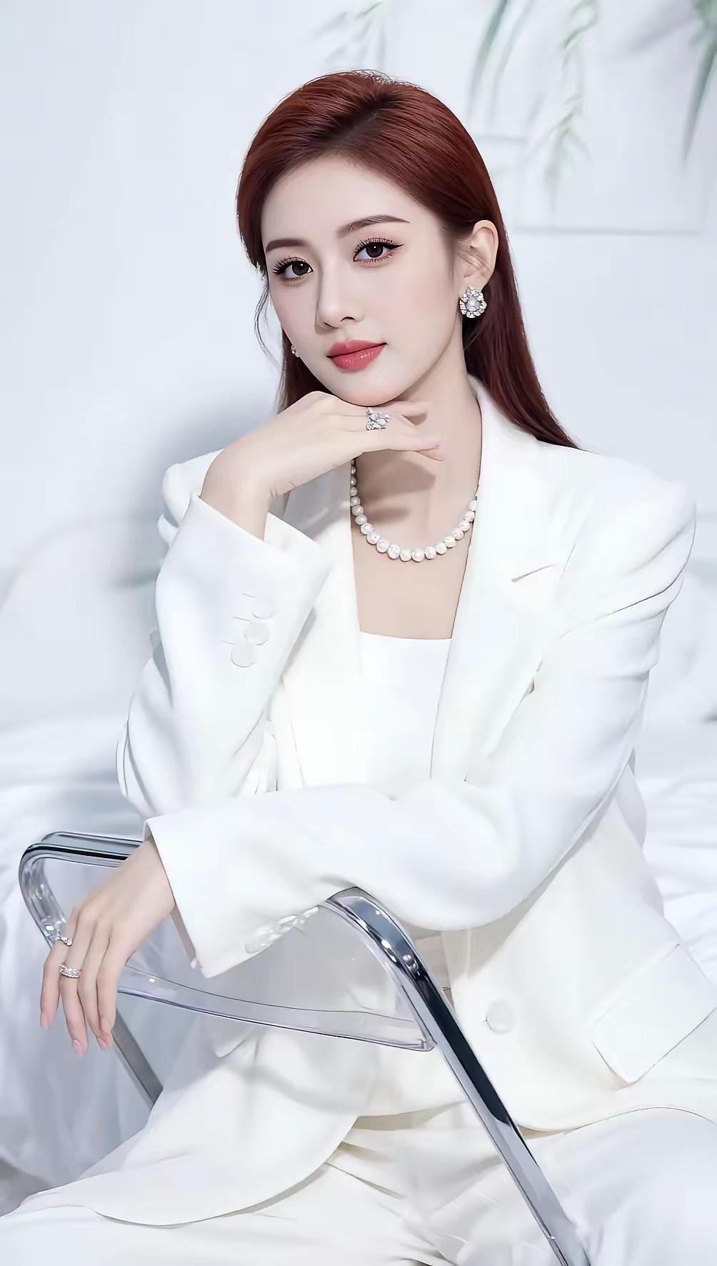 纯白西装里的优雅力量
她靠在透明椅子上，一身雪白西装就像月光洒在身上，剪裁利落，