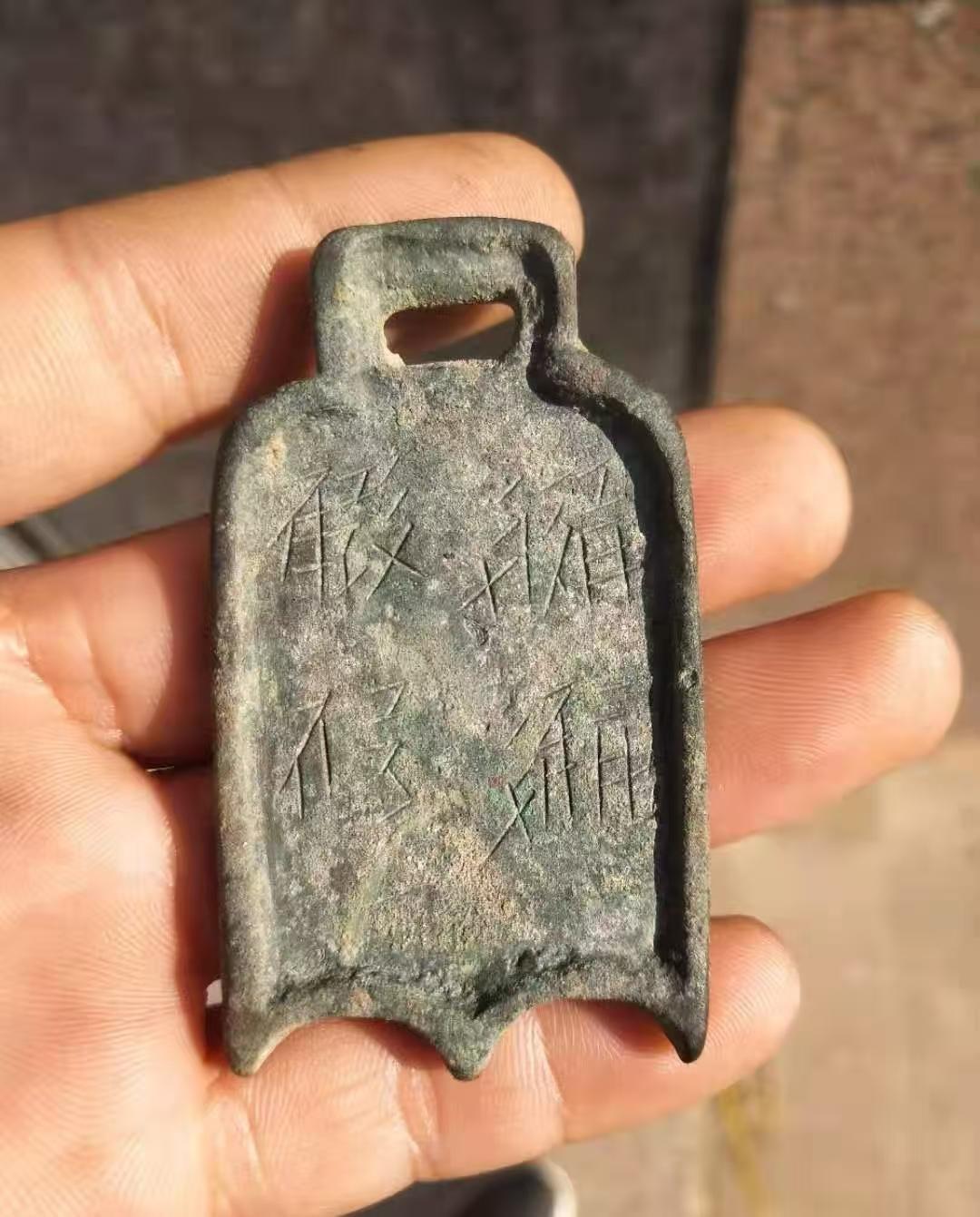 早上去地里掰玉米捡到个牌牌，上边有方形穿孔，看着像个小铲子。青铜色长方形，顶上方