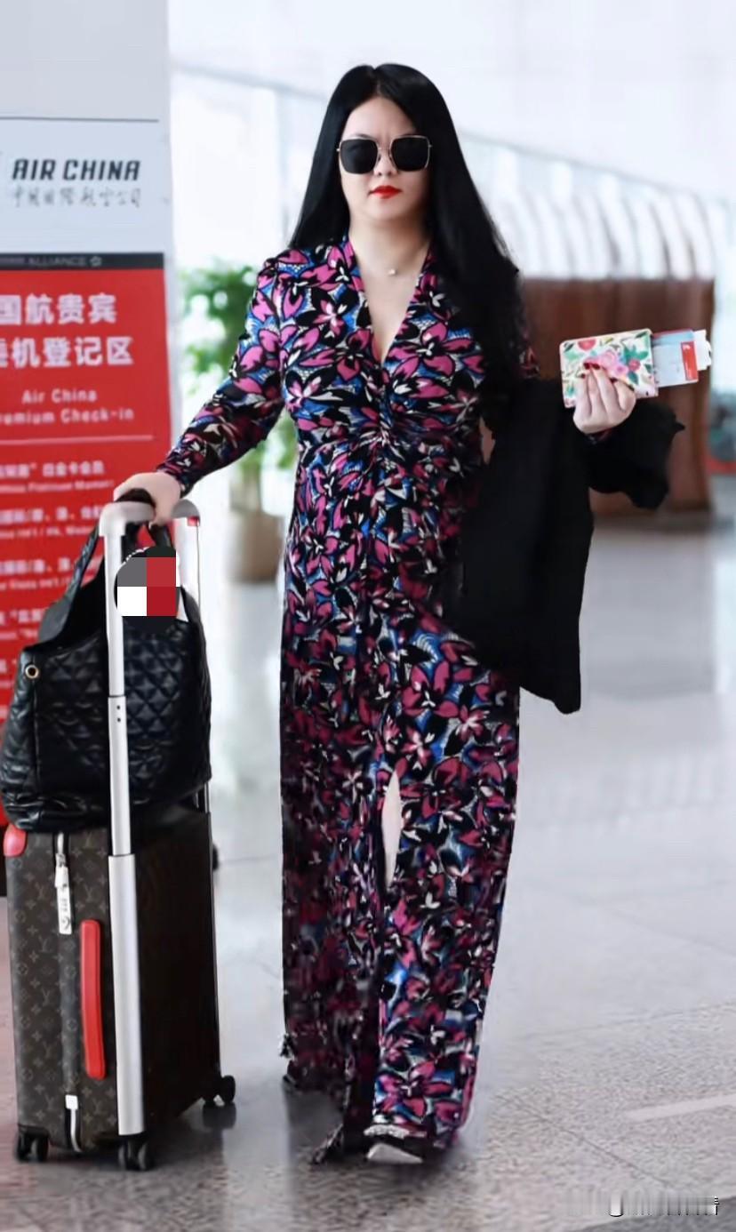 李湘独自一人出现在机场，被网友偶遇，这次依然还是她的经典造型，碎花大长裙，墨镜，