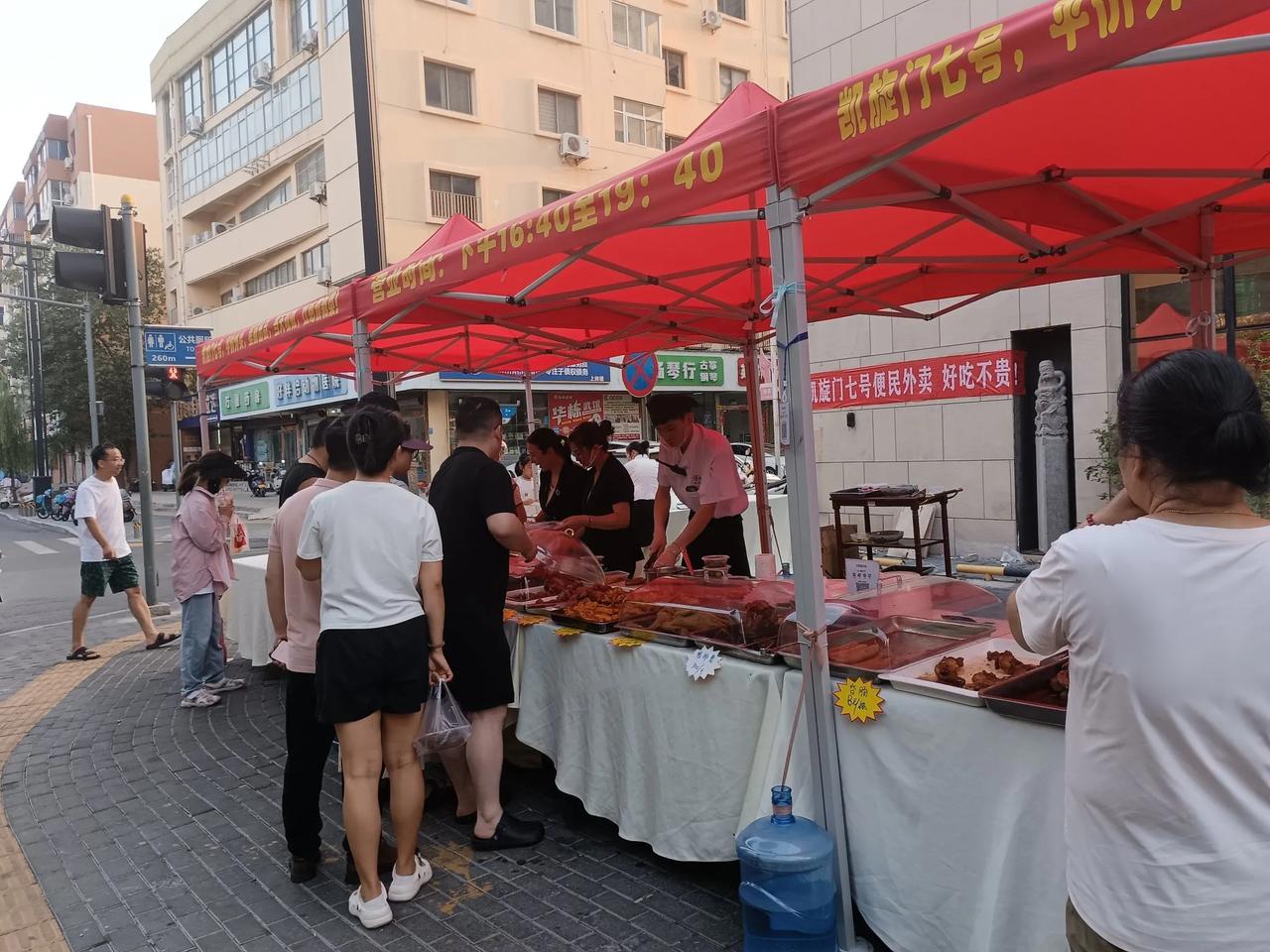 下班去菜市场，路过一家高档餐厅，发现竟然开始摆起路边摊。
一排桌子上，摆满了餐厅