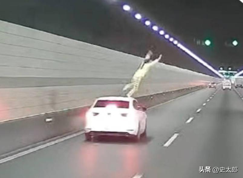 浙江钱江隧道，一辆白色轿车正常行驶，副驾女子突然降下车窗，爬上车顶，在高速车流中