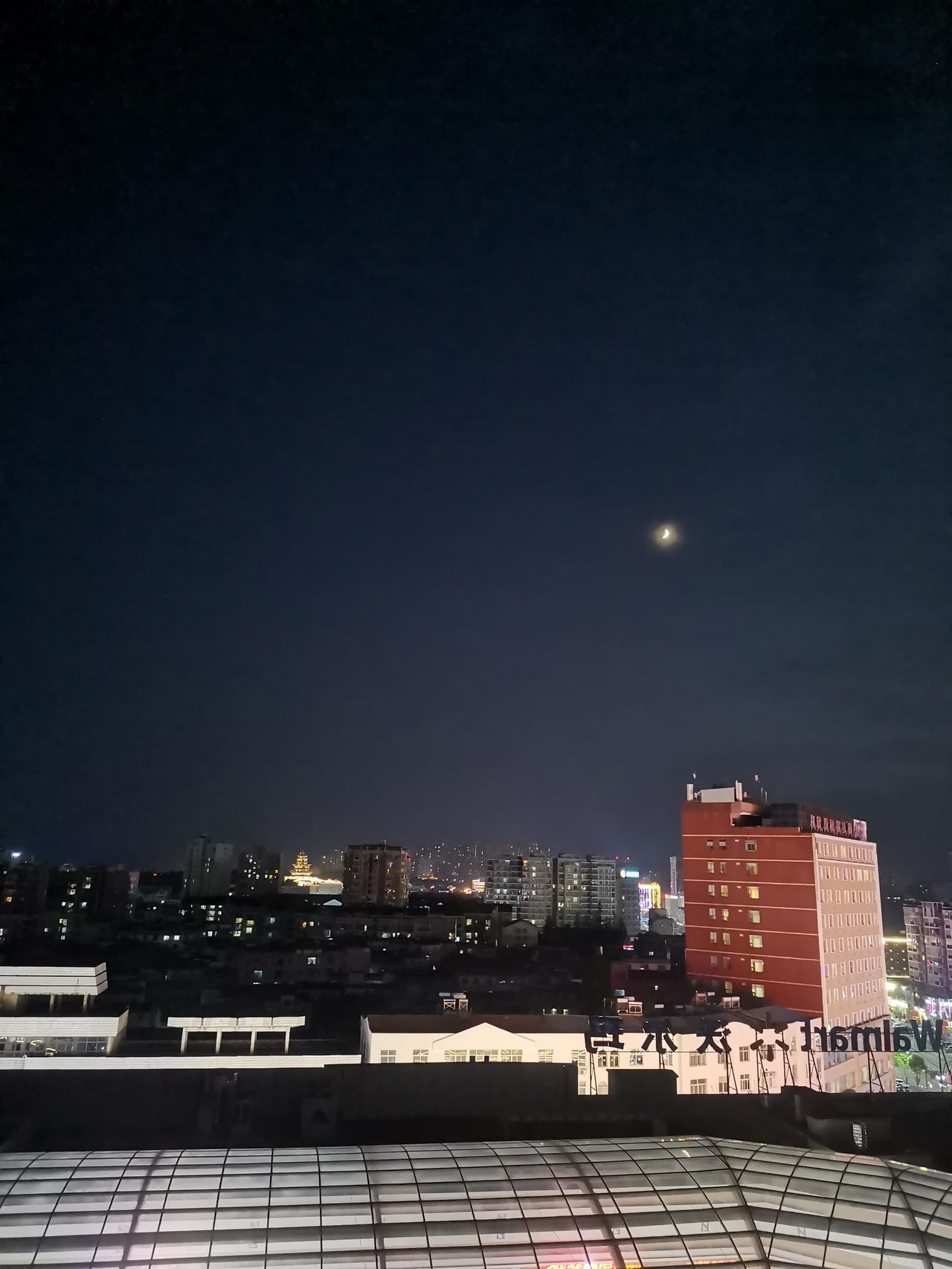 一轮明月高悬夜空，
俯瞰灯火通明的城市。
商超叫卖声此起彼伏，
商场空调外机发出