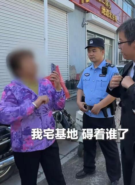 执法现场这位穿紫外套的大姐，举着手机对着执法人员拍，嗓门不小，理直气壮喊着 “我