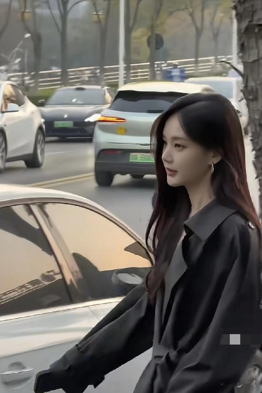 李一桐户外路透，她穿黑色风衣，长发披肩，气质干练
