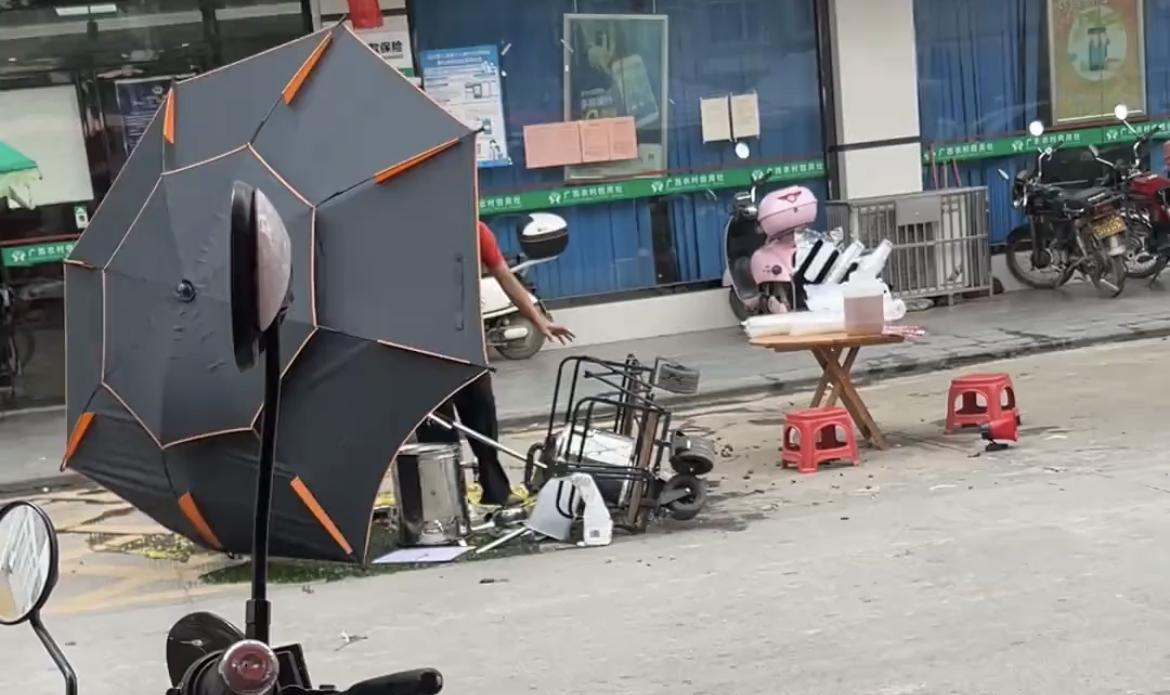 【玉林某镇阿姨摆摊的凉粉被一阵大风吹倒】

5月25日，玉林市某乡镇一阵大风把在