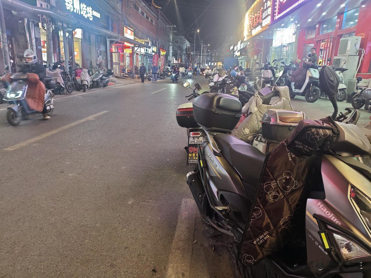 马路两侧停满了电动车，马路上人来人往相当热闹。马路两侧基本上都是各种餐馆：川湘菜