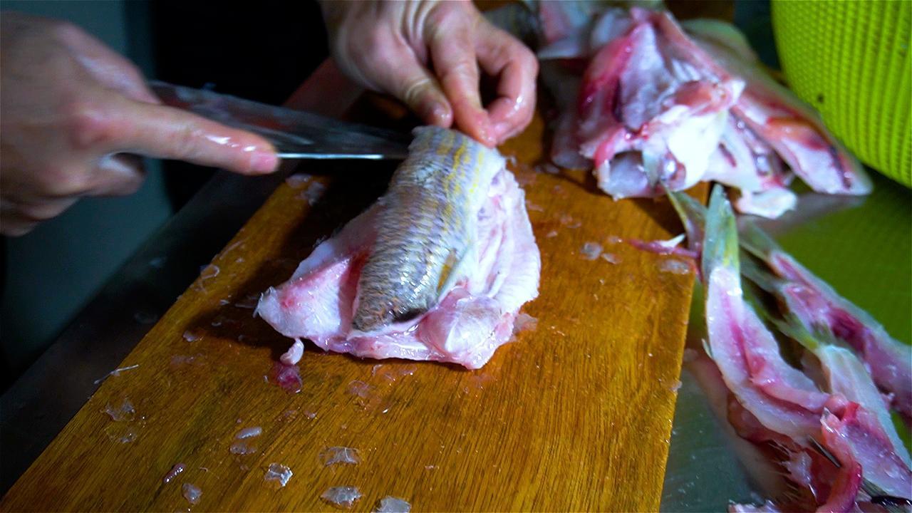 取深海狗母鱼，细致刮出鱼蓉，混合本地淀粉揉成团、搓长条、再切成薄片。不上猛火油炸