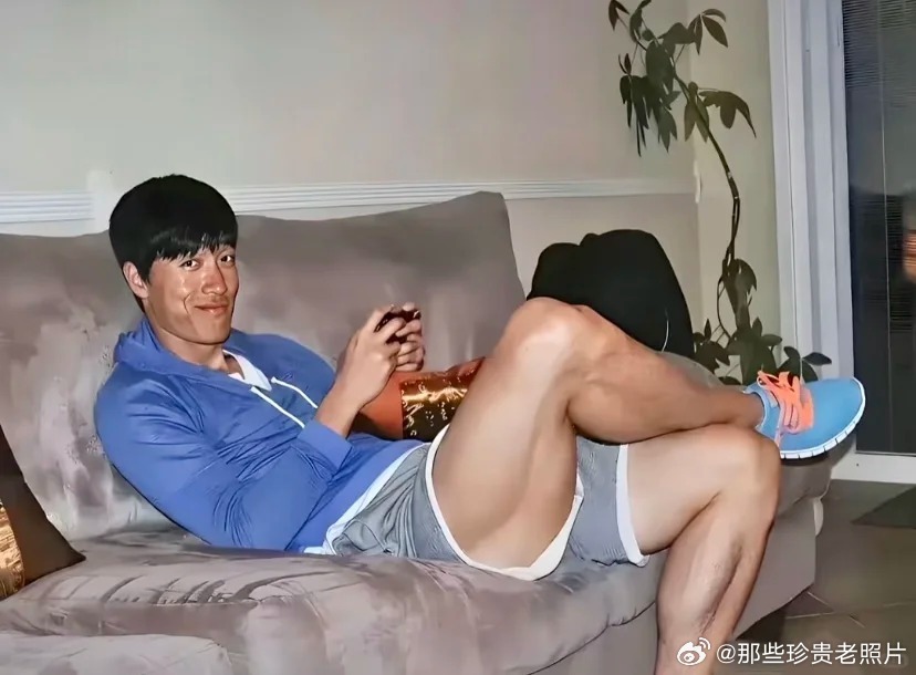 2013年，上海，冠军刘翔正躺在家里玩游戏。他穿着一件蓝色的运动上衣，灰色短裤，