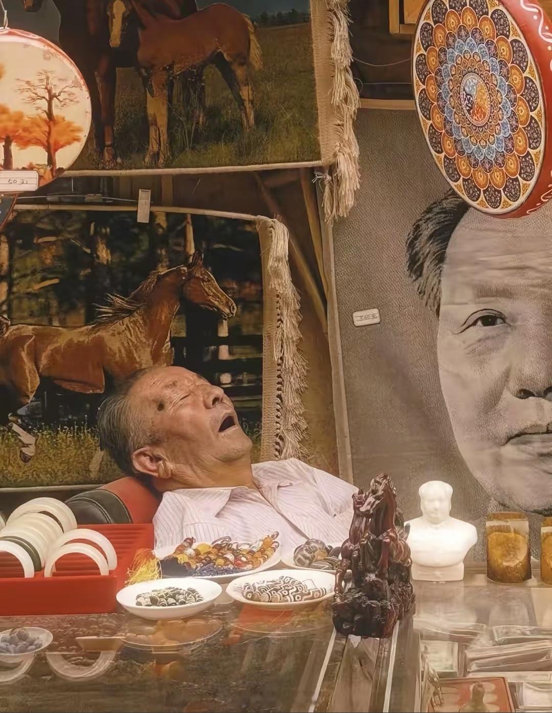 看到一位网友今天发的视频。新疆喀什古城一家店铺里，一位老者在教员画像下睡得正酣。