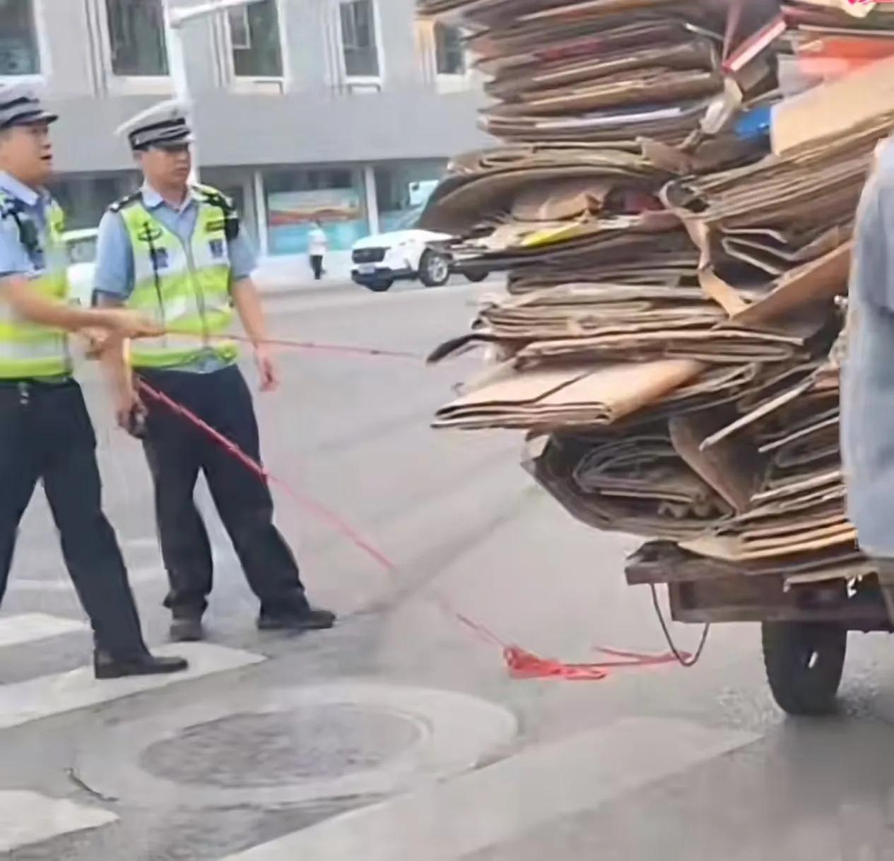 “这 2 个交警火了！”收废品的大爷骑着三轮车超载运纸板箱，被 2 名交警拦下。