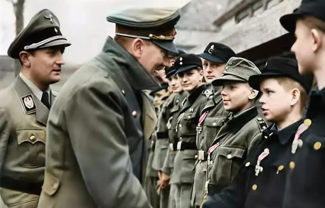 1945年4月20日，希特勒在总理府接见青年团成员 ，站在希特勒身后的是青年团团