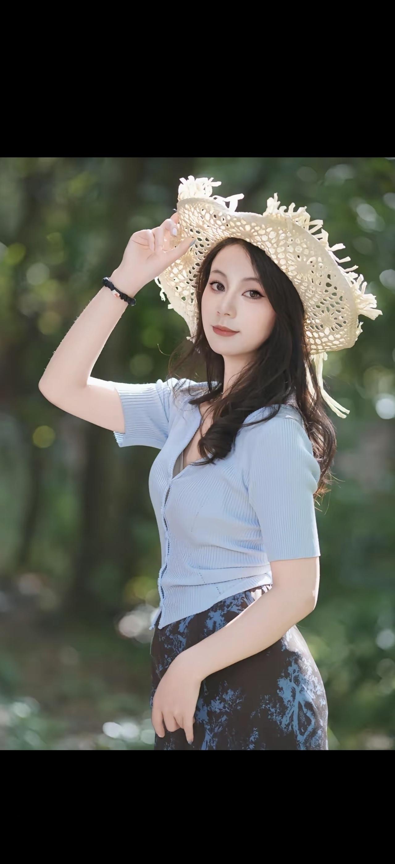 这姑娘戴着草帽在公园里摆姿势。