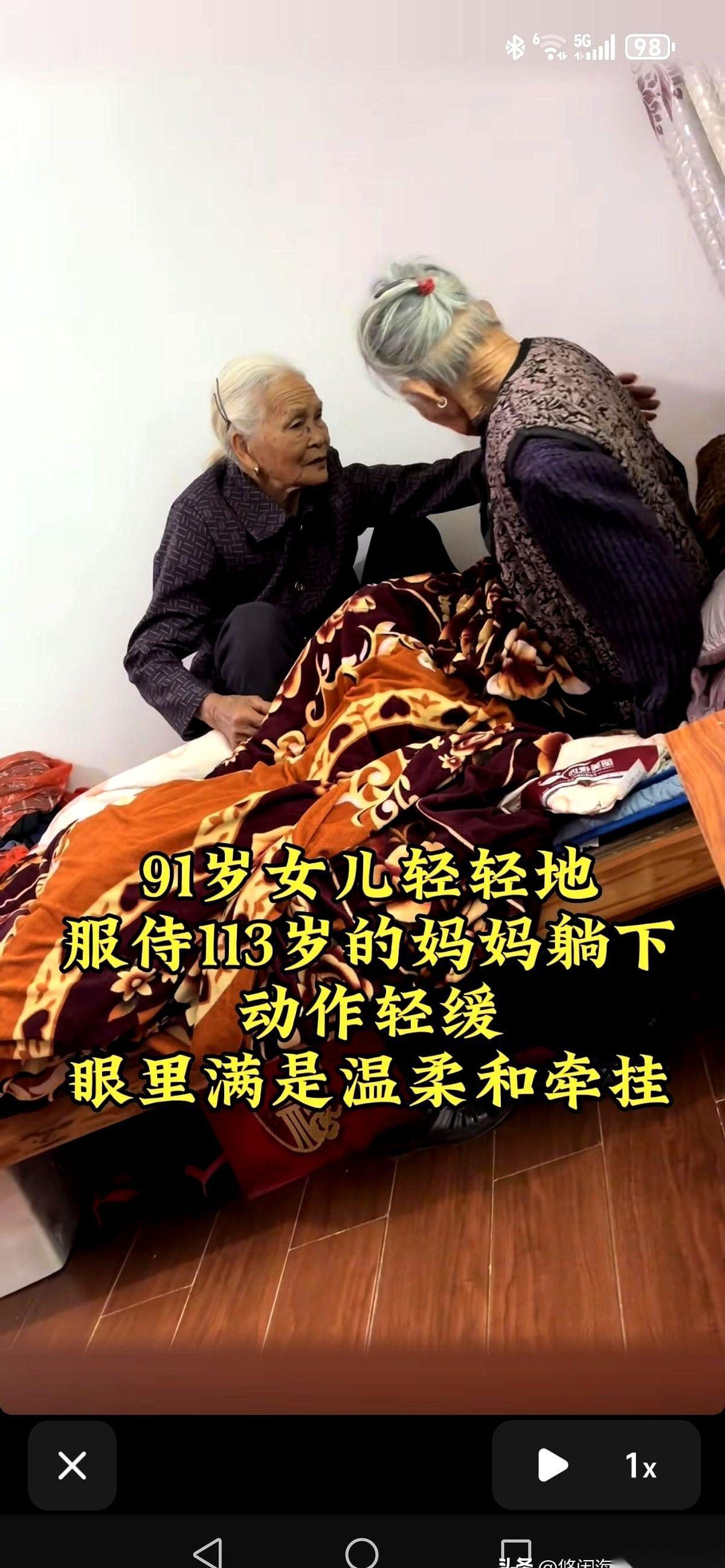 一头白发的91岁女儿，正俯下身，慢慢地、慢慢地扶着她113岁的妈妈躺下。
妈妈的