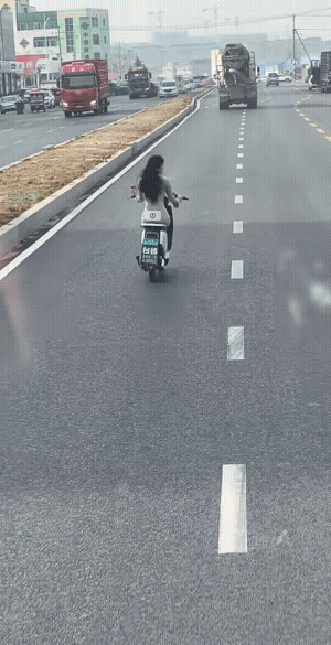 女子头盔也不戴，骑车还时不时的看一下手机。
视频中有问声，“是不是玉芬？”
不过