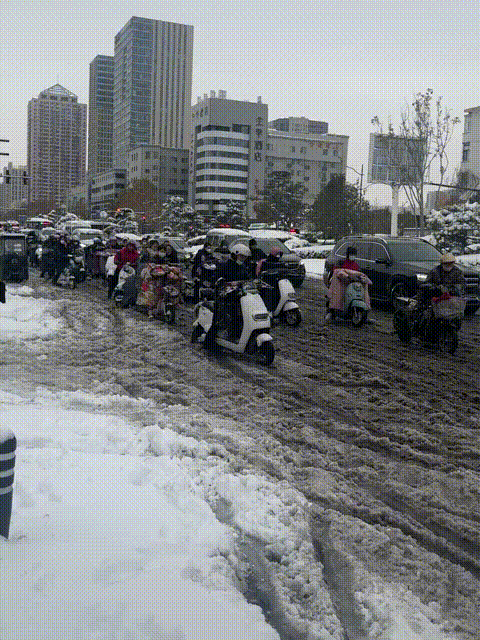 郑州一场大雪过后，路面没有及时清理，道路上的积雪开始融化，骑着电瓶车的上班族真是