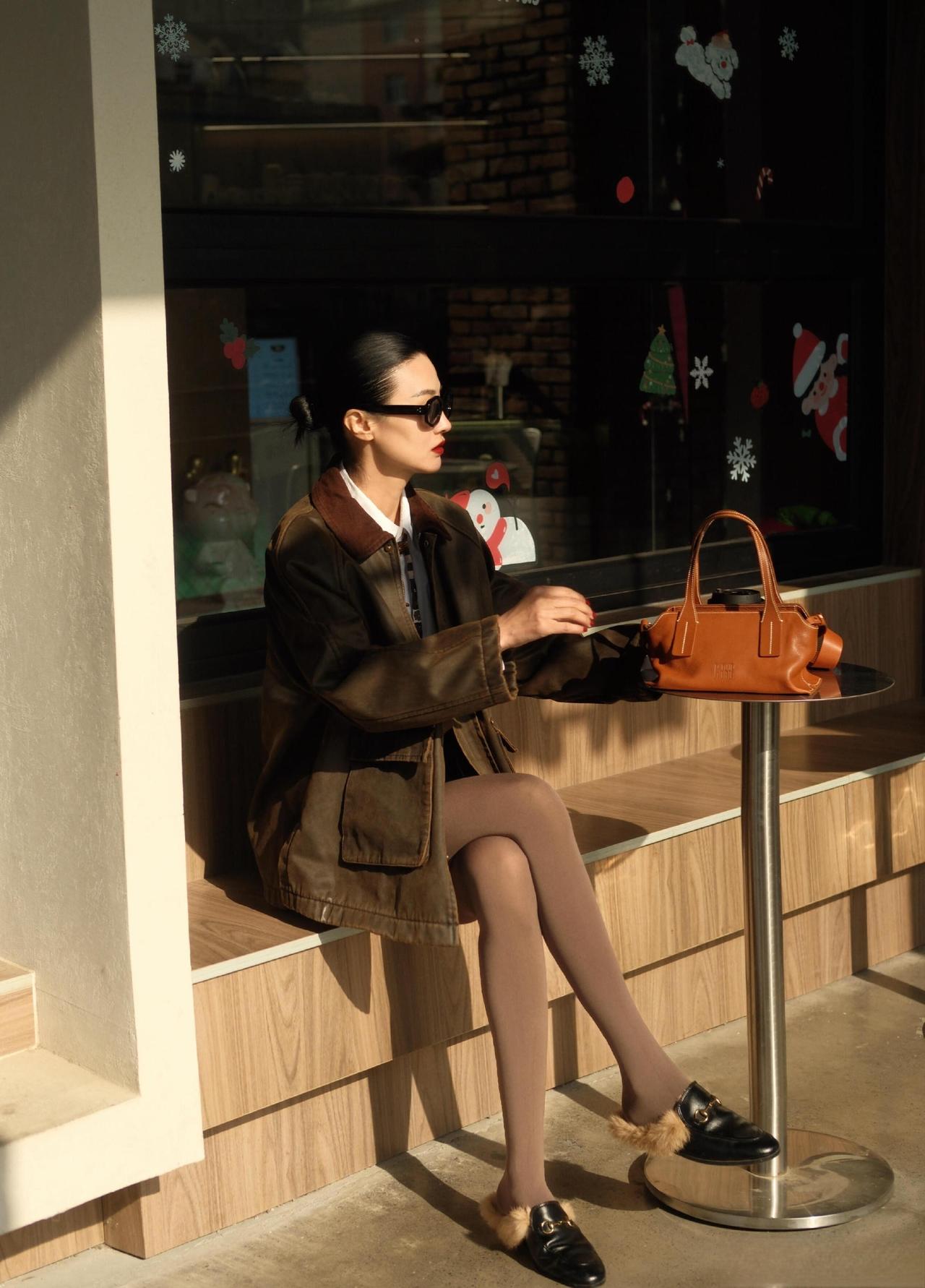 军绿外套自带随性气场，白衬衫+棕裙的叠穿添了利落质感，同色系袜子和毛毛鞋平衡了酷