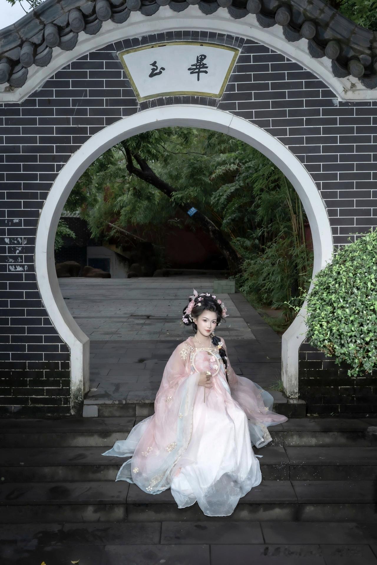 像是从山水画里走出的仙子。
身畔是碧波荡漾的江水，
身后是连绵起伏的青山。
不需