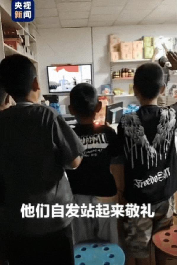 破大防了！新疆，一家社区商店里，几位小朋友趴在玻璃上偷看阅兵重播，老板娘干脆招呼
