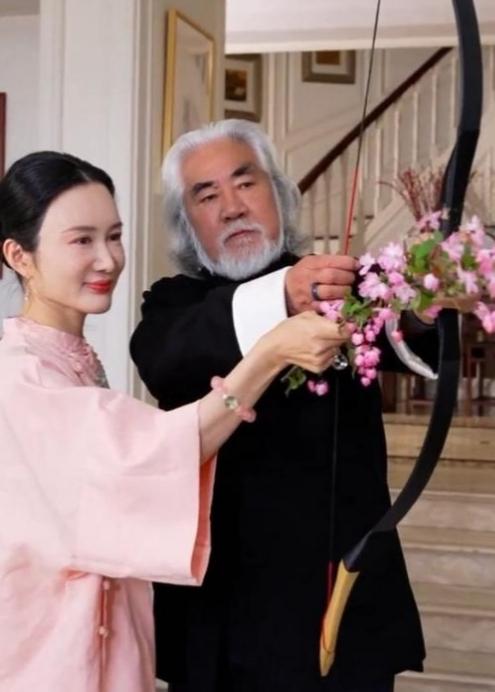 张纪中手把手教杜星霖玩弄桃花弓，两人面带微笑，嘴唇紧闭，这桃花满面的，是想证明什