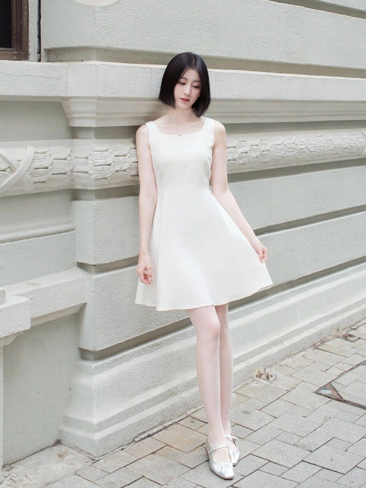 一身白色方领无袖A字裙是视觉焦点，简约的方领露出纤细锁骨，收腰设计恰好勾勒出腰线