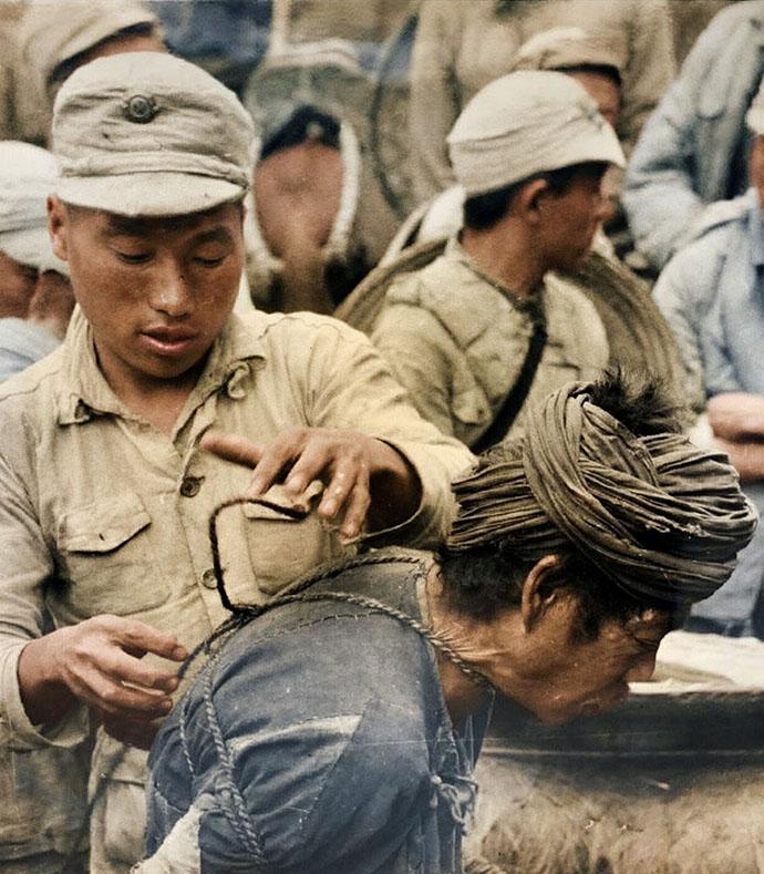 1944年，云南怒江前线附近的漾濞。一名中国远征军士兵正在师部给一名身着当地服饰
